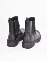 Bota tipo Chelsea de caña media, confeccionada en cuero sintético negro con paneles elásticos laterales y suela track dentada.