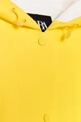 Cazadora impermeable de acabado engomado en color amarillo, con capucha ajustable, cierre frontal con botones a presión, bolsillos laterales y mangas largas ajustables.