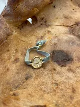 Pulsera dorada con dije redondo con la imagen de la Virgen de Fátima y cinta de terciopelo elástico color verde petróleo.