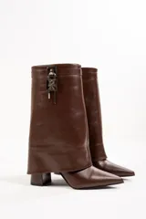 Botas de cuero color marrón con caña alta, punta fina y taco cuadrado. Presentan un aplique metálico con forma de candado en la parte superior de la caña.