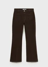 Pantalón tipo jeans de corte flare y diseño crop, color marrón. Presenta tiro medio, cierre frontal con cremallera y botón, trabillas para cinturón y dos bolsillos de parche en la parte delantera. El ruedo tiene un acabado deshilachado.