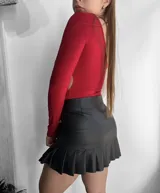 Mini pollera negra de cuero sintético con tablas y cierre lateral.