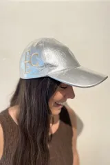Gorra tipo baseball confeccionada en cuero ovino italiano color dorado metalizado, con bordado del monograma PEC en el lateral.
