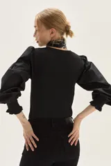 Top de calce ajustado color marrón, con escote cuadrado y mangas largas abullonadas de tela lisa. Los puños de las mangas son elastizados.