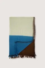 Bufanda tipo manta suave con diseño de bloques de color en tonos beige, azul y marrón, terminada con flecos en los extremos.