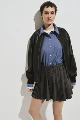 Camisa de corte oversized confeccionada en popelina de algodón con diseño de microcuadros. Presenta cuello clásico, bolsillo de parche en el pecho, cierre frontal con botones, hombros caídos y mangas largas con puños abotonados. Incluye canesú con pliegue en la espalda y bajo recto con aberturas laterales redondeadas.