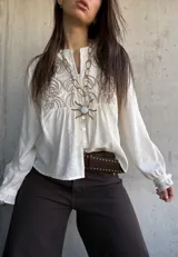 Camisa de lino color natural, con calce relajado, mangas largas amplias con puños fruncidos y delicado bordado geométrico en el frente.