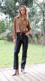 Pantalón de cuerina color beige, de corte recto y tiro alto, con detalle de costuras verticales en el frente.