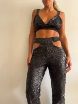 Pantalón de lentejuelas negro con aberturas en la cadera y corte recto.