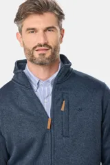 Campera de felpa gris melange, con interior de polar, cuello alto, cierre frontal completo y bolsillos laterales. Presenta detalles de apliques en cuero sintético en el pecho y la manga.