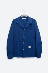 Chaqueta azul con textura seersucker, cuello con solapa, cierre con botones, bolsillo en el pecho y dos bolsillos de parche redondeados.