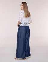 Bolero corto de encaje blanco con motivo floral y transparencias, escote en V pronunciado y mangas tres cuartos.