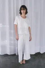 Pijama de algodón color blanco natural, compuesto por una remera de manga corta con bordado a contratono en el pecho y un pantalón largo de corte relajado con cordón ajustable en la cintura.