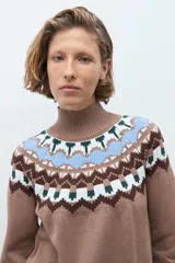 Polera de tejido de punto en color tostado, con diseño de estampado geométrico tipo nórdico en la zona del cuello, hombros y puños. Presenta cuello alto acanalado y mangas largas.