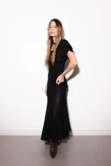Vestido largo negro de encaje transparente con diseño geométrico, mangas cortas con volados y cuello alto.