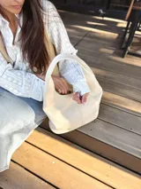 Bolso tote de cuero color crudo, con doble asa corta y diseño minimalista.