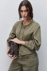 Campera azul marino de algodón, de corte relajado y largo corto, con cuello redondo, cierre frontal con botones metálicos, bolsillos delanteros y mangas largas con puños ajustables.