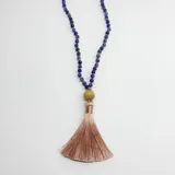 Japa mala compuesto por 108 cuentas de sodalita azul, con un dije gurú de madera y una borla de hilo de seda en color beige. El diseño incluye separadores de nudos en hilo color salmón.