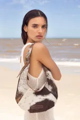 Cartera negra de cuero con forma de medialuna y tachas en zigzag.