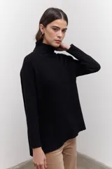 Polera de tejido de punto acanalado en color negro, con cuello alto y diseño de corte recto con largo asimétrico, más corto adelante y más largo atrás.