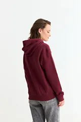 Canguro liso de color bordó, con capucha ajustable mediante cordones y bolsillo frontal tipo canguro.