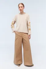 Sweater de punto color gris claro, confeccionado en lambswool. Presenta cuello redondo, combinación de puntos en el frente y bordados florales hechos a mano en las mangas.