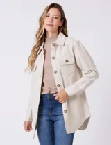 Sobrecamisa de corte amplio confeccionada en tejido suave al tacto, color beige. Presenta cuello de solapa, cierre frontal con botones efecto carey, dos bolsillos frontales con solapa y mangas largas con puños abotonados. El ruedo es redondeado en los laterales y cuenta con canesú en la espalda.