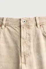 Jeans flare fit de tiro medio confeccionados en denim de algodón color beige, con cinco bolsillos, efecto salpicaduras y bajo irregular.