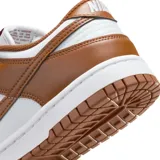 Championes Nike Dunk Low con diseño bicolor en blanco y marrón. Presentan una silueta clásica de perfil bajo, confeccionados en cuero con el icónico logo de la marca en los laterales, cierre de cordones y suela de goma resistente.
