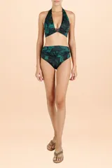 Top de bikini estilo halter con diseño de ondas en tonos negro y turquesa. Presenta un detalle de avío metálico con piedra central en el escote y tiras para anudar al cuello.