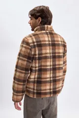 Buzo de sherpa con diseño a cuadros en tonos marrones y beige, cuello alto con medio cierre frontal y bolsillos laterales.