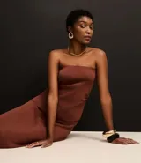 Blusa marrón sin breteles, de corte ajustado y bajo asimétrico, con textura acanalada y laterales fruncidos.