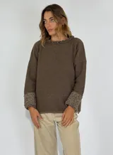 Sweater gris de manga larga con cuello redondo y puños con detalle de volados de lana rizada.