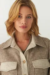 Camisa estilo leñador color beige con textura en espiga, de manga larga, con cuello clásico, cierre frontal con botones, dos bolsillos de parche con solapa abotonada en el pecho y puños abotonados. Confeccionada en lana fina sin teñir.