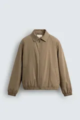 Cazadora regular fit de tejido técnico y mezcla de algodón con ligero acolchado interior, color marrón. Presenta cuello solapa, manga larga, bolsillos de vivo en la cadera, bolsillo interior, y acabados elásticos en puños y dobladillo. Cuenta con cierre frontal de cremallera.