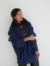 Buzo color crudo con cuello de piel sintética color crema, abertura parcial con cierre de cuero marrón y hebilla dorada, puños con ajuste de cuero marrón y bolsillos laterales.