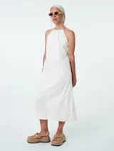 Vestido midi blanco de algodón, con cuello halter y breteles finos ajustables. Corte recto y falda acampanada.