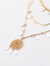 Collar de tres niveles en color dorado, con cadena de eslabones y dijes colgantes en forma de gota en tonos plateado y blanco, finalizando con un dije central circular calado.