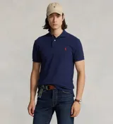 Remera polo Ralph Lauren de corte clásico, color azul marino con el logo del jinete bordado en rojo en el pecho. Cuenta con cuello y puños acanalados, y tapeta corta con botones.