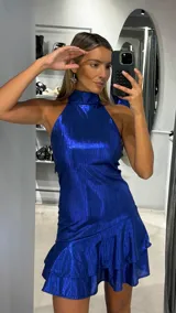 Vestido corto de fiesta color azul eléctrico, con cuello halter y falda con doble volado en el ruedo. Confeccionado en tejido brillante con textura.