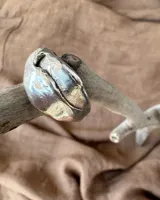 Anillo grueso de alpaca color plateado, con forma irregular y superficie texturizada.