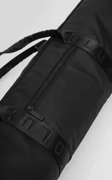 Bolso cilíndrico porta yoga-mat color negro, confeccionado en cordura de alta densidad. Cuenta con correas regulables grabadas con el logo de la marca, manijas cortas para agarre manual, compartimento principal con cierre metálico reforzado y un bolsillo trasero pequeño con cierre para objetos de valor.