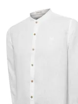 Camisa de manga larga confeccionada en lino orgánico, con cuello mao y cierre frontal de botones en tono madera. Presenta un diseño minimalista con bordado sutil al tono en el pecho.