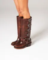 Botas altas de cuero marrón con acabado desgastado, múltiples hebillas metálicas laterales y tacón bajo cuadrado.