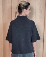 Cardigan de lana lambswool color azul oscuro, con cuello clásico, cierre frontal de botones y mangas cortas con terminación acanalada. Presenta dos bolsillos frontales y diseño de punto tejido.