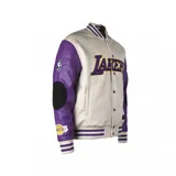 Campera bomber de algodón color crema con mangas de cuero sintético color violeta. Tiene el logo de Los Angeles Lakers bordado en el pecho y parches en los codos.