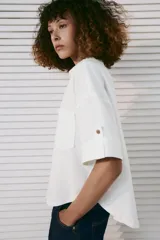 Camisa crop de mezcla de lino color blanco, con cuello solapa, escote en V, manga corta con trabilla, bolsillos de plastrón en el delantero y cierre frontal de botones.