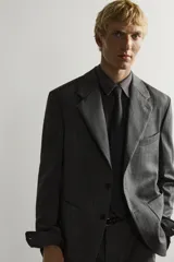 Blazer de corte relaxed fit de Zara, confeccionado en 100% lana color gris. Cuenta con cuello de solapas de muesca, manga larga, bolsillos de parche en la cadera, bolsillo de vivo en el pecho y cierre frontal con un botón.