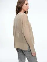 Sweater de tejido fino y semitransparente con hilo brillante. Presenta cuello redondo, hombros caídos y mangas largas amplias con un ajuste relajado y caída fluida.