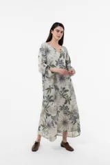 Vestido largo de lino de calce relajado y silueta fluida, con estampa botánica en tonos verdes y azules sobre fondo beige. Cuenta con escote en V y mangas amplias.